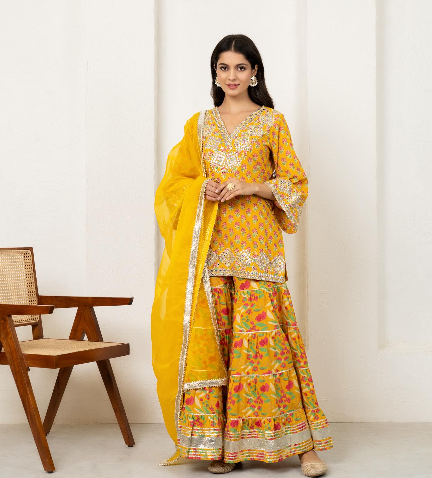 Step into the spotlight with our yellow cotton short kurti and sharara set, exquisitely adorned with